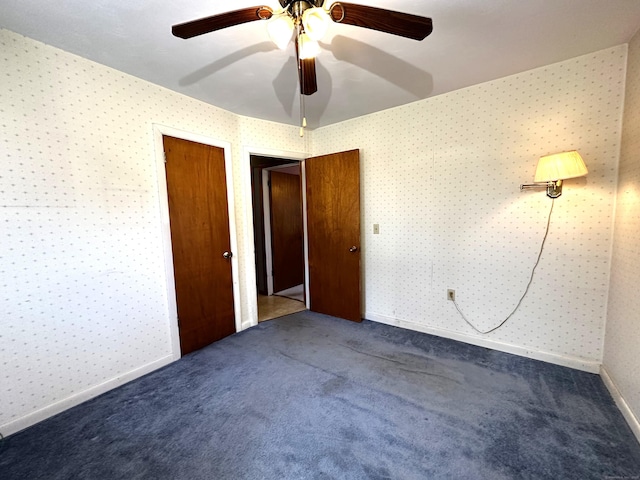 unfurnished bedroom with wallpapered walls, baseboards, ceiling fan, carpet, and a closet