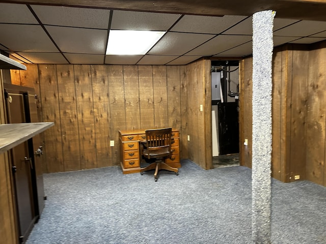 home office featuring carpet, wood walls, and a paneled ceiling