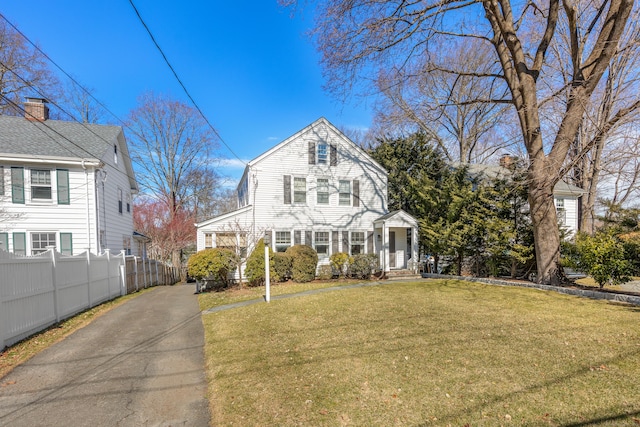 dutch colonial featuring a front yard, fence, and aphalt driveway