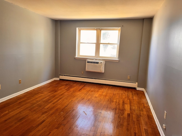 spare room with baseboards, baseboard heating, an AC wall unit, and hardwood / wood-style floors