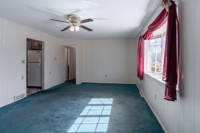 carpeted spare room with visible vents and ceiling fan