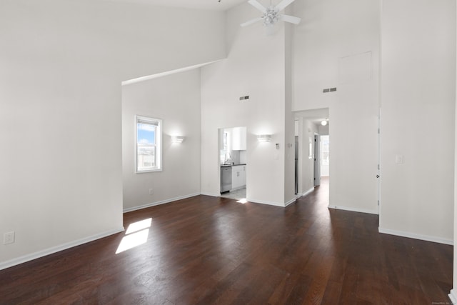 unfurnished living room with ceiling fan, visible vents, baseboards, and dark wood-style floors