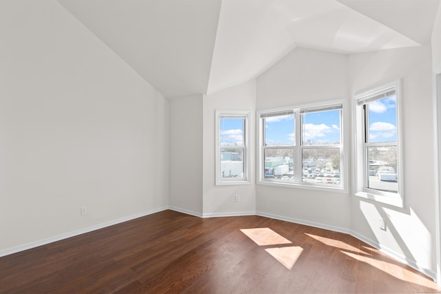 spare room with vaulted ceiling, baseboards, and dark wood-style flooring