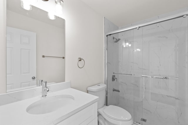 full bathroom featuring vanity, toilet, and a marble finish shower