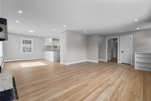 unfurnished living room featuring light wood finished floors, recessed lighting, a baseboard heating unit, and baseboards