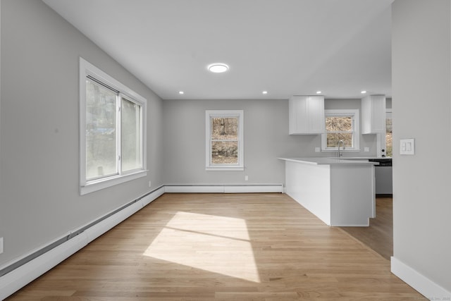 kitchen featuring light countertops, white cabinets, light wood-type flooring, and a baseboard radiator