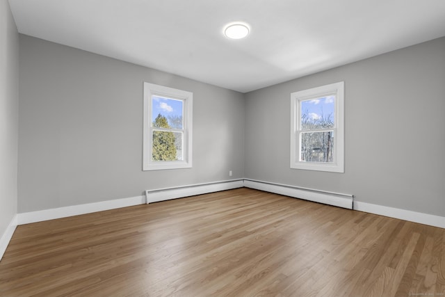 empty room with a baseboard radiator, baseboards, and wood finished floors