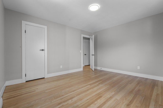 unfurnished room with baseboards and light wood-style flooring