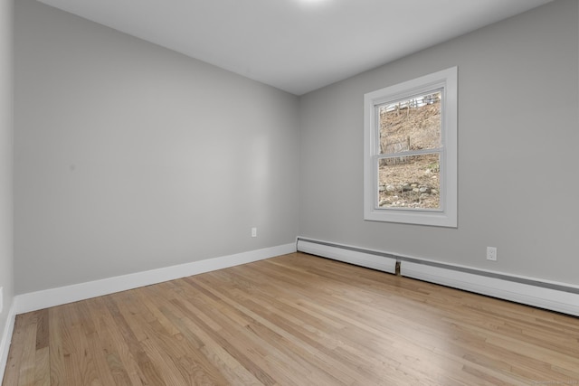 empty room with baseboards, baseboard heating, and wood finished floors