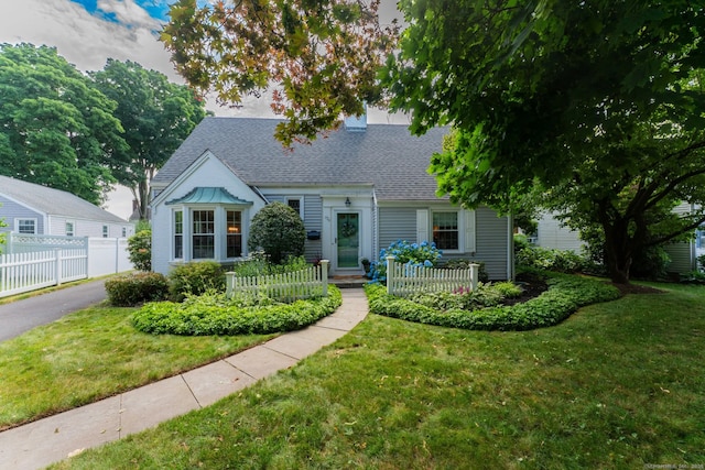 cape cod home featuring a shingled roof, a front yard, and fence