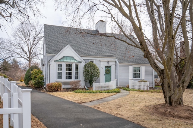 view of front facade with a chimney, a shingled roof, and fence