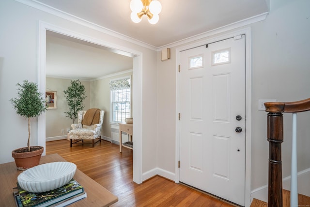 foyer entrance featuring light wood-type flooring, ornamental molding, radiator heating unit, baseboards, and a chandelier