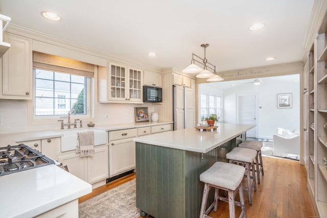 kitchen featuring a sink, a kitchen bar, plenty of natural light, and black microwave