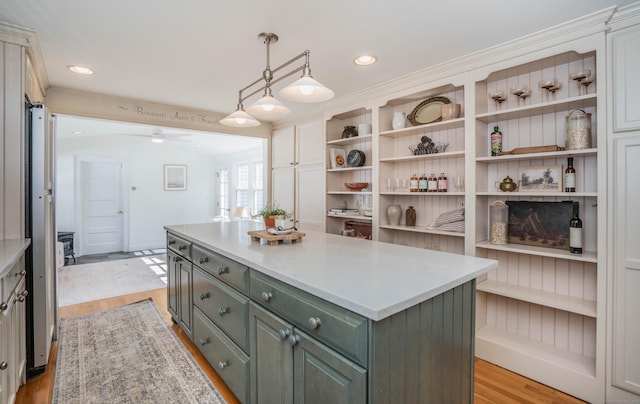 kitchen featuring light wood finished floors, a kitchen island, recessed lighting, light countertops, and hanging light fixtures