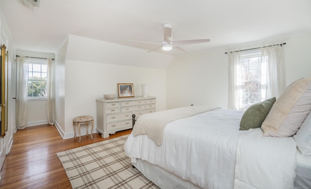 bedroom featuring ceiling fan, baseboards, lofted ceiling, and light wood-style floors