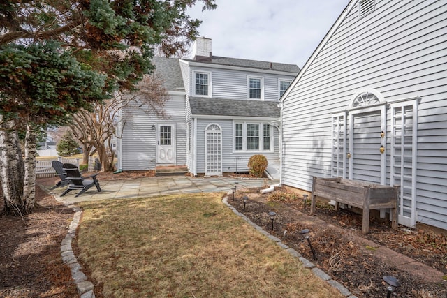 back of property with entry steps, a patio, fence, a yard, and roof with shingles