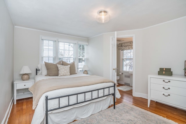 bedroom featuring ornamental molding, radiator heating unit, baseboards, and wood finished floors