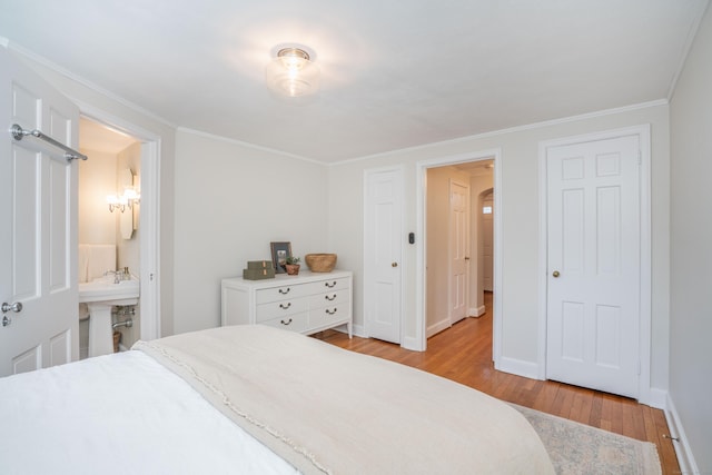 bedroom featuring connected bathroom, baseboards, crown molding, and light wood finished floors