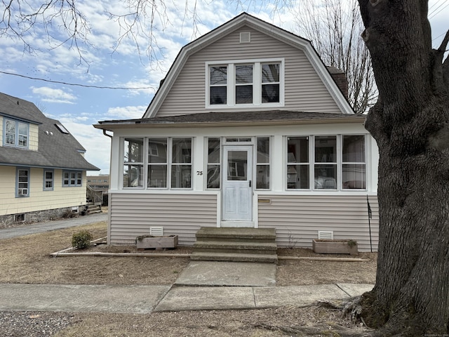 dutch colonial featuring a gambrel roof, entry steps, a shingled roof, and a sunroom