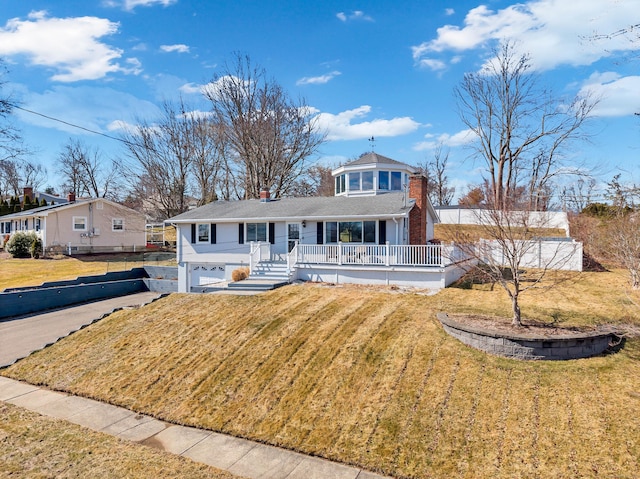 view of front of house with driveway, a porch, a chimney, a front lawn, and a garage