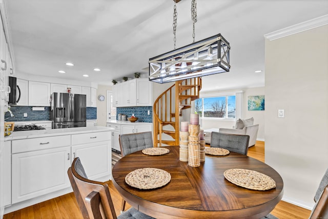 dining space with crown molding, baseboards, light wood-type flooring, stairs, and recessed lighting