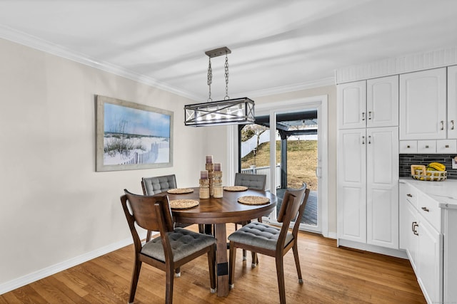 dining room with baseboards, crown molding, and light wood finished floors