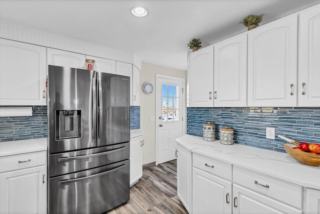 kitchen featuring decorative backsplash, stainless steel fridge, and white cabinetry