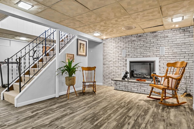 living area with stairs, wood finished floors, baseboards, and a fireplace