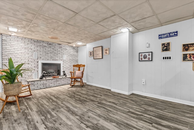 sitting room with a brick fireplace, wood finished floors, and baseboards