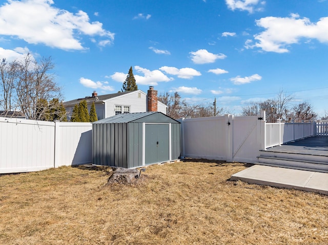 view of yard featuring an outdoor structure, a storage shed, a fenced backyard, and a gate