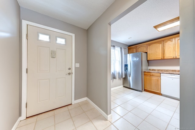 foyer featuring light tile patterned flooring, a textured ceiling, and baseboards