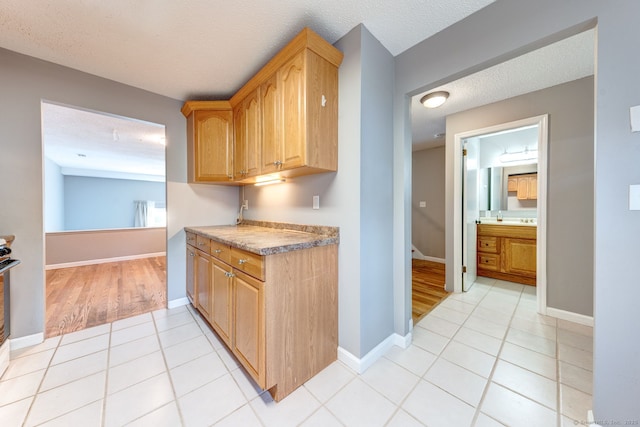 kitchen featuring light tile patterned floors, baseboards, range with electric stovetop, and a textured ceiling