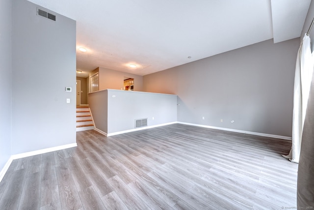 unfurnished room featuring visible vents, stairway, baseboards, and wood finished floors