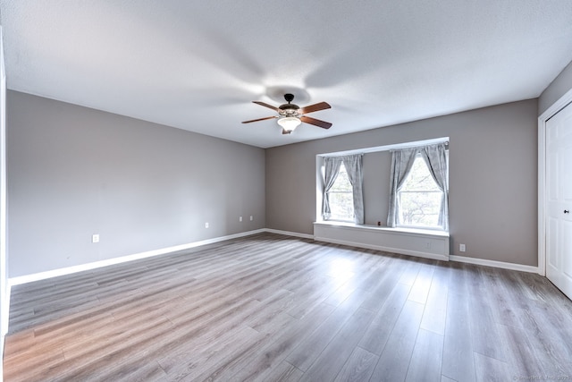 unfurnished room with a ceiling fan, wood finished floors, and baseboards