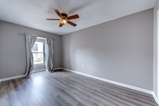 spare room featuring ceiling fan, a textured ceiling, baseboards, and wood finished floors