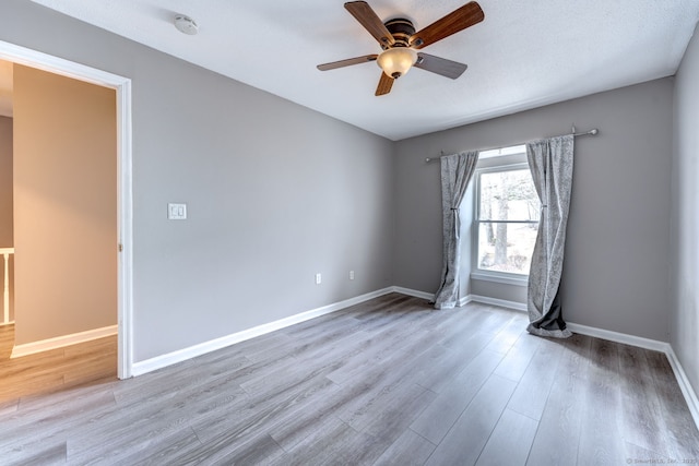 empty room featuring a ceiling fan, baseboards, and wood finished floors