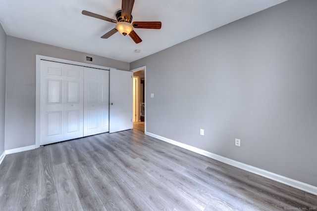 unfurnished bedroom featuring a closet, baseboards, wood finished floors, and a ceiling fan