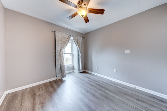 spare room with a ceiling fan, wood finished floors, and baseboards