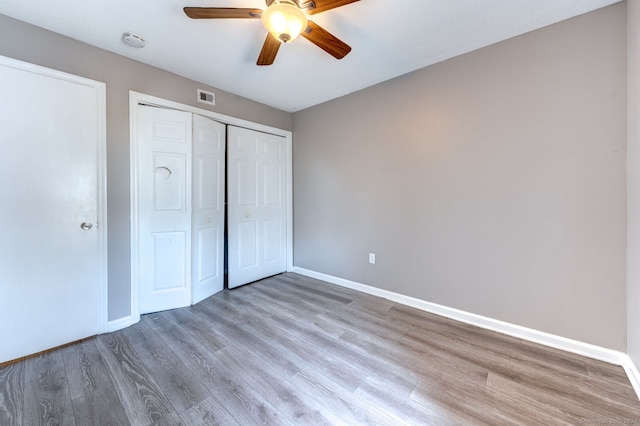 unfurnished bedroom featuring visible vents, a ceiling fan, wood finished floors, a closet, and baseboards