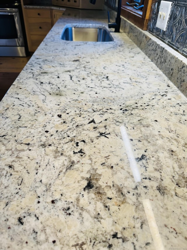 interior details with electric range, a sink, and light stone countertops