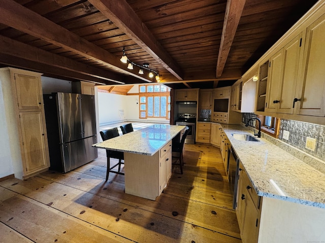 kitchen with beamed ceiling, stainless steel appliances, light wood-type flooring, and a sink