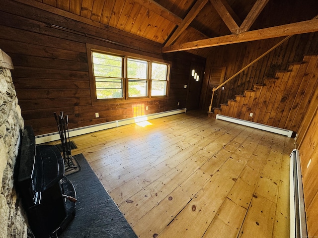 unfurnished living room featuring wood walls, hardwood / wood-style floors, stairs, and a baseboard radiator