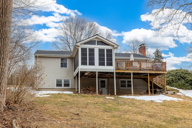 rear view of house with stairway, a sunroom, a chimney, a deck, and a lawn