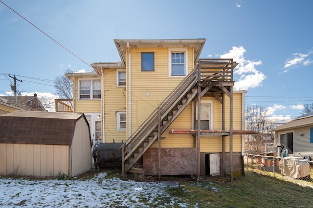 back of property featuring a storage unit, an outbuilding, stairs, and fence