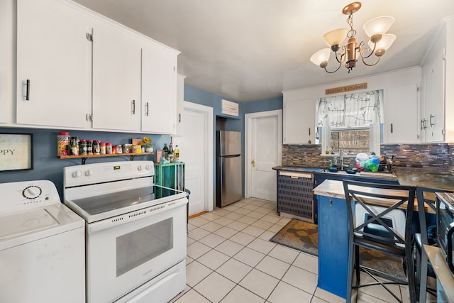 kitchen with washer / dryer, freestanding refrigerator, light tile patterned flooring, electric range, and white cabinetry