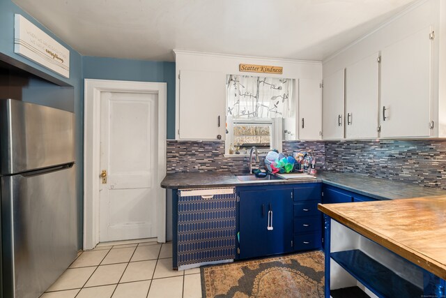 kitchen with a sink, white cabinetry, freestanding refrigerator, light tile patterned floors, and dishwashing machine