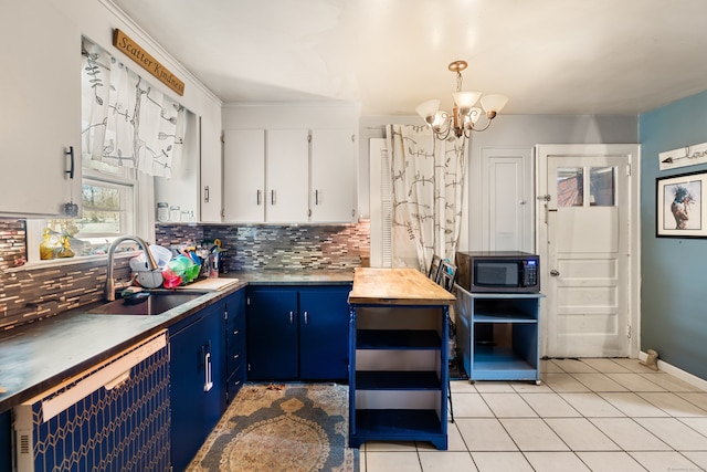 kitchen featuring blue cabinets, a sink, backsplash, white cabinetry, and light tile patterned floors