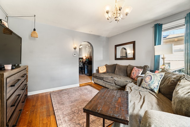 living room featuring hardwood / wood-style flooring, baseboards, arched walkways, and a chandelier