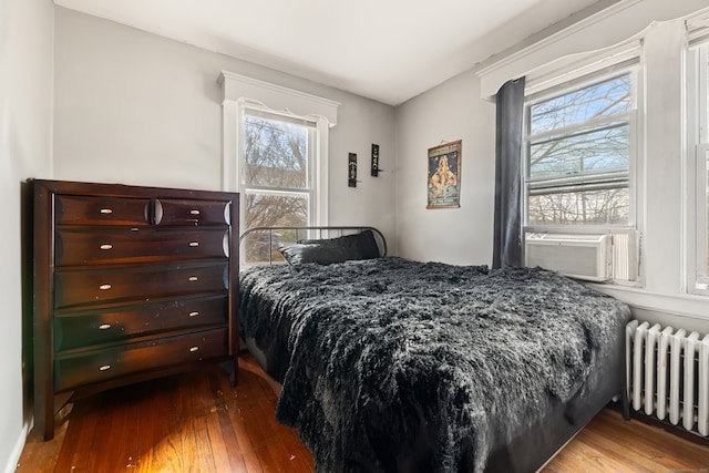 bedroom featuring cooling unit, radiator, and hardwood / wood-style floors