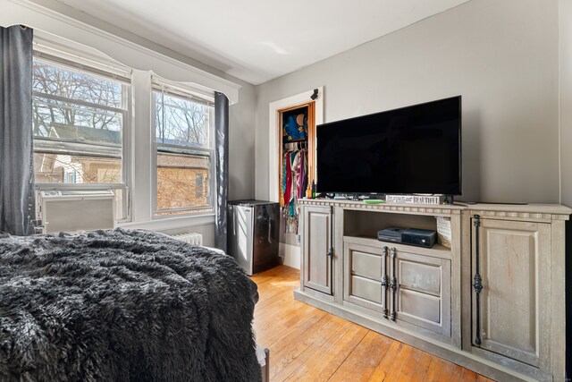 bedroom featuring cooling unit, fridge, and light wood-style floors